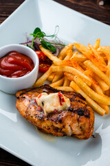 Canvas Print - Fried chicken fillet with French fries, onion, cherry tomatoes and ketchup, closeup.