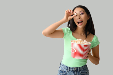 Poster - Young Asian woman with bucket of popcorn on white background