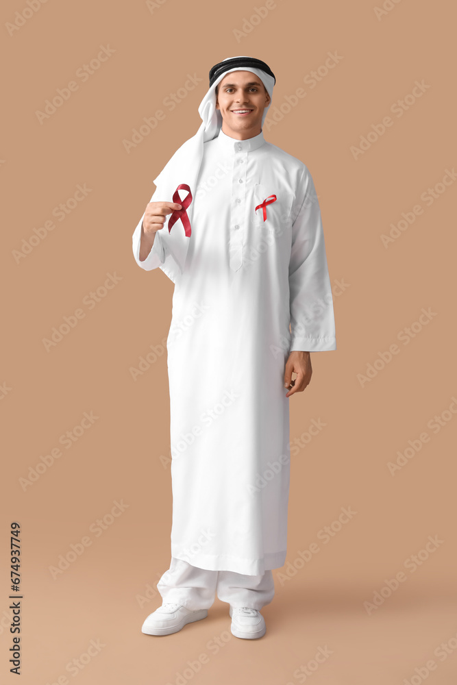 Handsome Muslim man with red ribbons on brown background. AID awareness concept