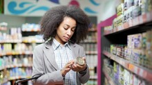 Woman Examines The Composition Of The Product Goods Female Customer Shopper Reading Label On Can Of Canned Food In Supermarket Studies And Reads Information Considers Makes Choices In The Store