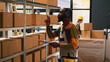 © DC Studio - Storehouse manager checking cargo list near shelves with boxes, examining products stock in packages. Male worker listening to music and working on supply chain inspection, retail store.