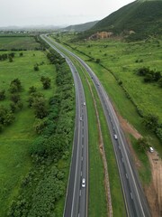 Wall Mural - Aerial view of a tree-lined highway leading to a vast expanse of green grass in the distance