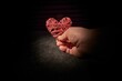 Person holding a woven heart against a black backdrop