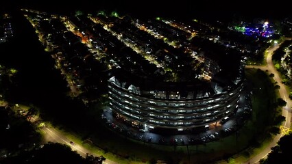 Canvas Print - Drone footage over illuminating round modern building at night in the city