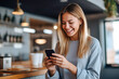 © MVProductions - A happy caucasian woman standing in her kitchen white looking at good news on her smartphone
