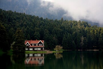 Poster - Idyllic house with a red roof on the edge of a tranquil lake, providing a picturesque view