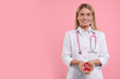 Doctor with stethoscope holding pink ribbon on color background, space for text. Breast cancer awareness
