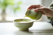 The close up detail of a person is pouring green tea in a bowl from a traditional teapot in a relaxed atmosphere. Generative AI.