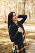 © Mila - A beautiful girl in jeans and a plaid shirt walks in a birch grove. Portraits of a brunette girl in nature, in the autumn forest