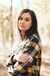 © Mila - A beautiful girl in jeans and a plaid shirt walks in a birch grove. Portraits of a brunette girl in nature, in the autumn forest