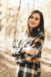© Mila - A beautiful girl in jeans and a plaid shirt walks in a birch grove. Portraits of a brunette girl in nature, in the autumn forest
