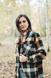 © Mila - A beautiful girl in jeans and a plaid shirt walks in a birch grove. Portraits of a brunette girl in nature, in the autumn forest