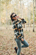 © Mila - A beautiful girl in jeans and a plaid shirt walks in a birch grove. Portraits of a brunette girl in nature, in the autumn forest