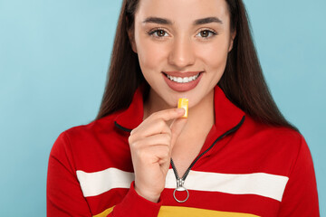 Poster - Happy young woman with bubble gum on light blue background