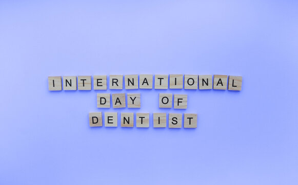 February 9, International Day of dentist, minimalistic banner with the inscription in wooden letters on a blue background