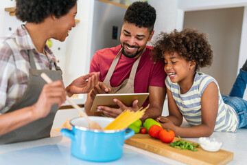 Wall Mural - Happy black family in the kitchen having fun and cooking together. Healthy food at home.