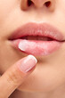 © Lustre Art Group  - Perfect natural lip makeup. Close up photo of woman applying with finger hygienic lip balm. Moisturizing treatments for dry lips.