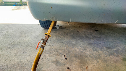 Close-up detail view of fuel autogas pump gun connected with noozle adapter to car tank to refill at car gas filling station. Refueling vehicle with liquefied lpg or lng product. Safety technology