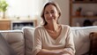 © id512 - an attractive middle-aged woman sits on her couch in modern cozy living room, good health, a positive mood, and delightful emotions