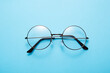 Glasses in round thin metal frame isolated on blue surface.