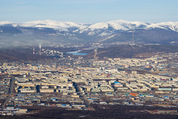 Wall Mural - Top view of the city of Magadan. A large northern city in a valley among the mountains. Many buildings. Snow-capped mountains in the distance. Magadan, Magadan region, Russian Far East.