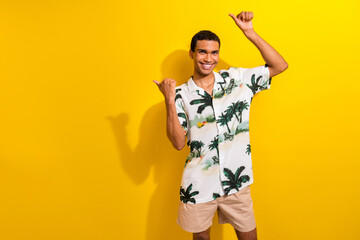 Wall Mural - Portrait of cheerful guy with ring in nose dressed tropic print shirt directing at offer empty space isolated on yellow color background