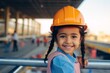 Happy indian child girl in an engineer hard hat at a construction site. Work process, construction of a house