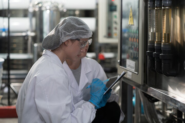 Two female worker wearing uniform, hairnet working and checking of water pump system, pipes station, Water pressure system, water tank at production line in industry factory