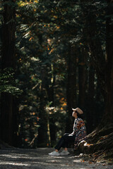 one woman sitting relax meditation under the forest tree, relaxation lifestyle with nature connection, living outdoor with green wood, natural healing and therapy for healthy activity