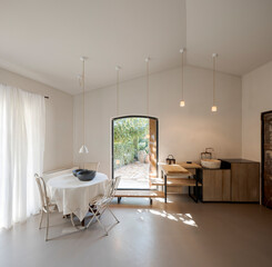 Wall Mural - Front view of the kitchen area with a table and chairs on the left, furniture on the right. The interior is modern and minimalist.