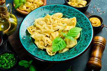 Wall Mural - Homemade pelmeni, ravioli, dumplings with meat in butter sauce and basil. Top view.