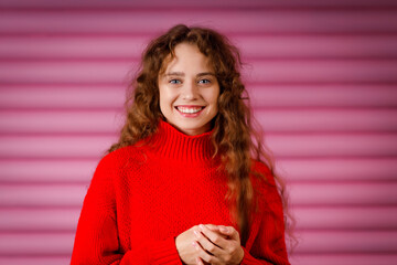 Happy smiling young adult woman wearing winter warm red sweater indoors looking at camera with joyful smile