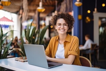 happy woman sitting at table with laptop in cafe