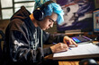 Young boy with blue hair studying at a desk, computer glowing nearby