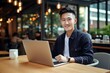 © vasyan_23 - happy asian man sitting at table with laptop in cafe