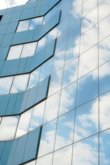 modern facade of glass and steel with reflections. abstract or graphic photo of the sky with clouds 