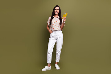 Poster - Full length photo of mature smiling beautiful business lady hold smartphone working remote influencer isolated on khaki color background