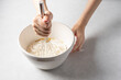Woman's hand mixing dough into bowl. Cooking, baking