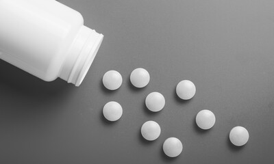 Wall Mural - Medical pills are pouring out of a bottle. On a black and white background.