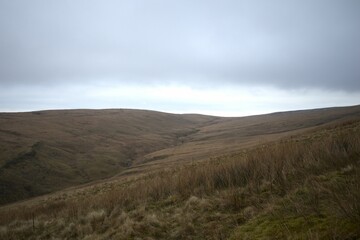 Wall Mural - Scenic view of a valley with green hills on a cloudy day in Wales, UK