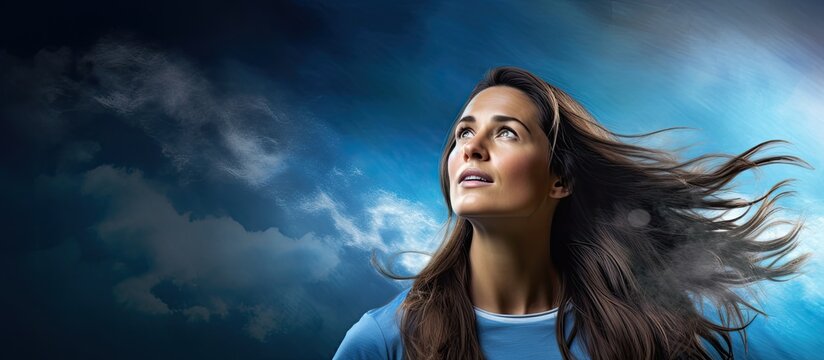 A woman with flowing hair gazes up at the sky captivated by a digital banner displaying a graphic of a football in front of a backdrop of blue clouds and light It s a celebration of the wor