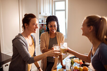 Young female friends drinking fresh juice from vegetables in the kitchen