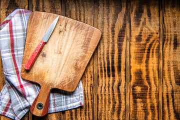 Wall Mural - Wood cutting board with linen napkin and knife on wooden table with copy space, top view