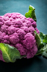 Wall Mural - Fresh organic purple cauliflower cabbage with leaves on old rustic green table background, top view