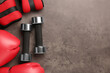 Metal dumbbells, boxing gloves and weights on brown textured table, flat lay. Space for text