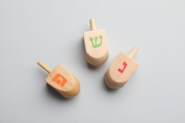 Wooden dreidels on light background, flat lay. Traditional Hanukkah game