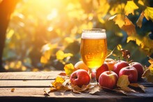 A refreshing glass of cider basking in the sunlight with an arrangement of freshly harvested apples and fall foliage