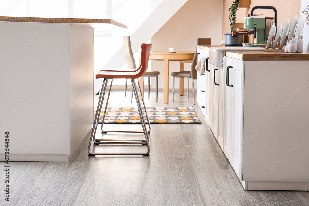 Interior of modern kitchen with bar stools near table
