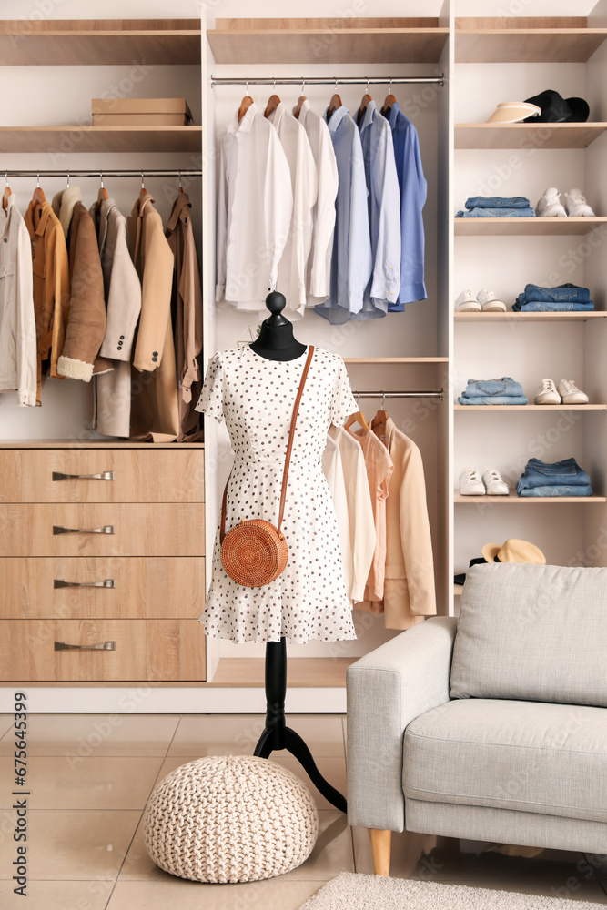 Interior of boutique with stylish clothes, mannequin and sofa