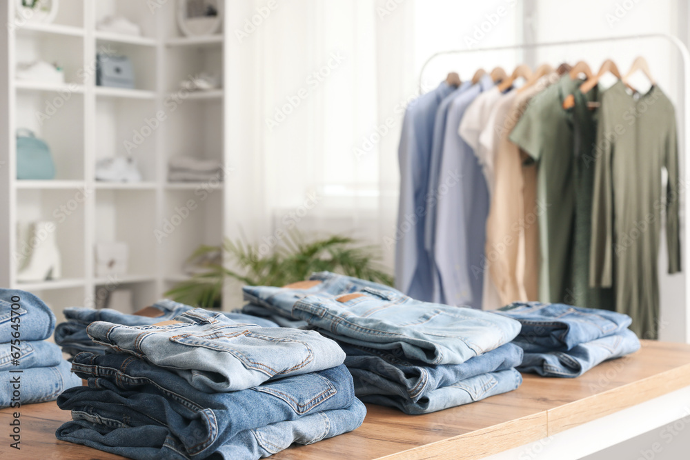 Table with stylish jeans pants in modern boutique, closeup